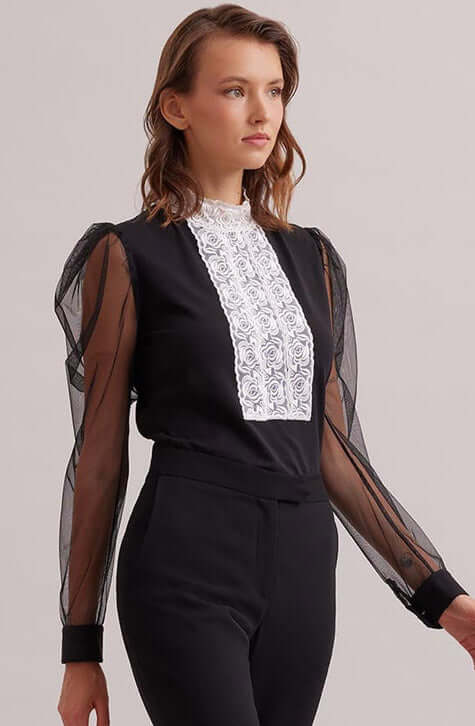 The EPOPEE is a black jersey pullover top with a center ribbon appliqué front made of a triple lace rose column that extends to create a mock neck. The pleated shoulders give way to a voluminous sheer sleeve that are finished with black jersey single French cuffs that allow for cufflinks. The EPOPEE features a hidden zipper at the back for closure.