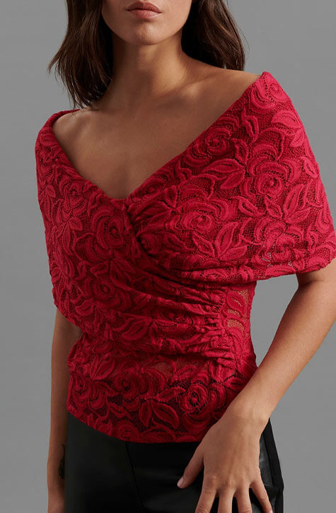 The JINKOA is an faux wrap top in pink lace. The JINKOA is enhanced with a subtle v-neckline and an off the shoulder sleeve.