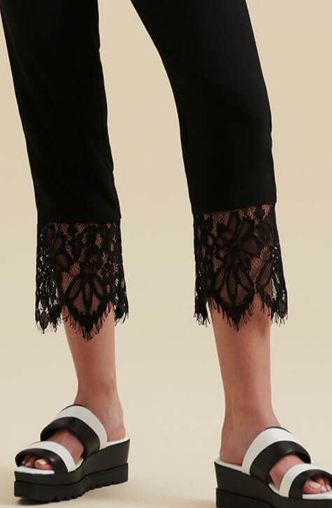 The GABI are ankle length black crepe pants enhanced with a wide delicate eyelash scalloped black lace along the hem of each pant leg. These ankle length pants feature a center-front zipper with a hook and eye for closure and Italian side pockets.